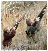 Two people hunting out in tall grass. 